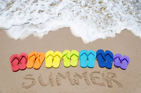 夏天签及彩色拖鞋在沙滩上