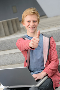 十几岁的中学生与笔记本电脑拇指向上