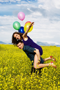 幸福的夫妇用黄色字段上的气球