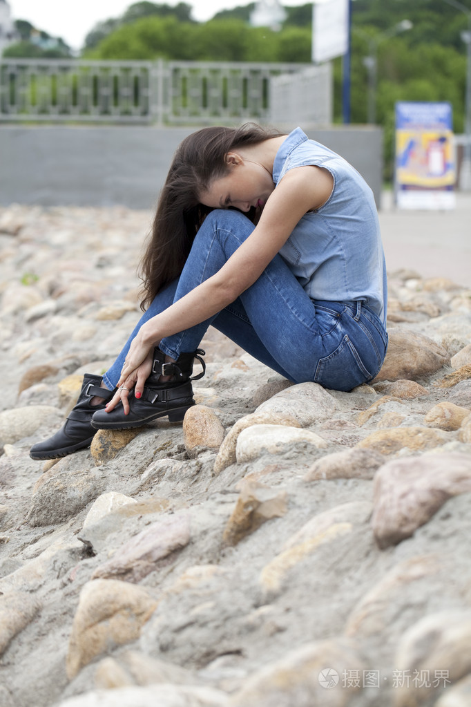 悲伤的女人坐在石头上