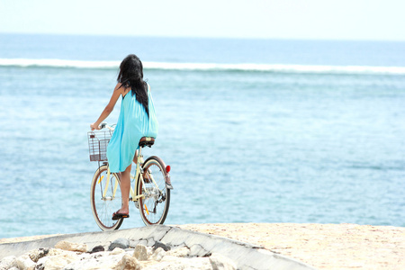 开心的女人骑着自行车在海滩