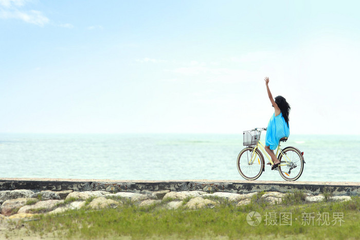 开心的女人骑着自行车在海滩