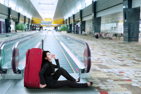 女商人坐在机场的地板上