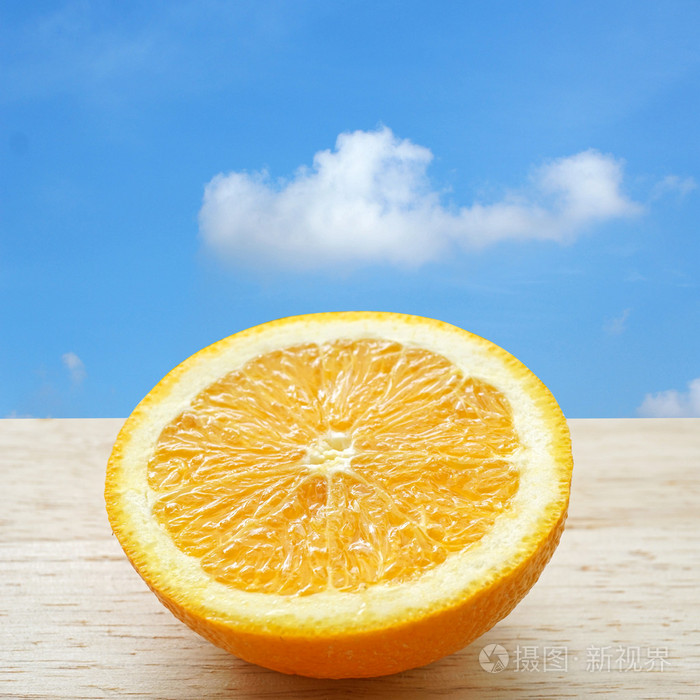 木制的桌子，与蔚蓝的天空中的背景上的半个橙子
