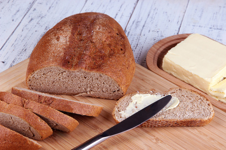 黑麦面包与黄油的切菜板上木制的背景