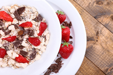 草莓与巧克力木制的桌子上的碗里的健康谷物