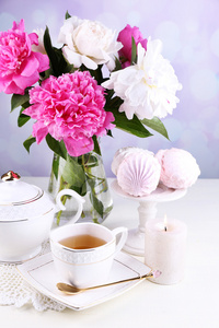 艳丽的牡丹在花瓶 杯子和棉花糖，在桌子上，在明亮的背景上茶的组成