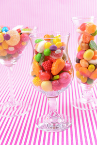 不同的多彩水果糖果在粉红色的背景上的眼镜