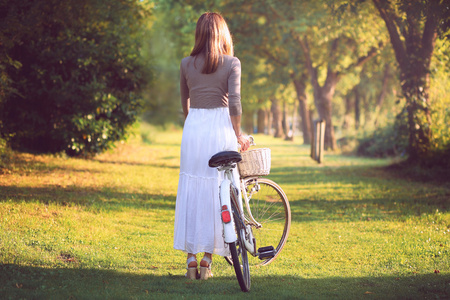 在夕阳的光线的老式自行车的女人