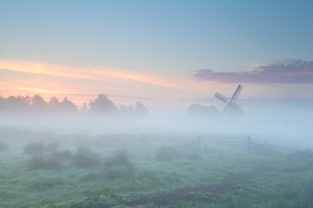 在密集的晨雾中的风车剪影图片