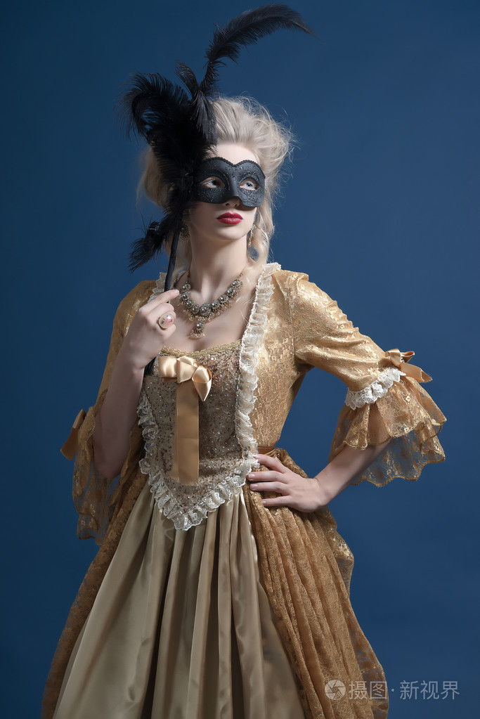 复古的巴洛克式时尚女人穿着金色衣服.抱着一只黑