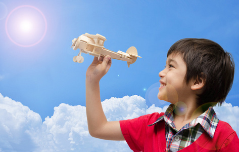 小男孩玩飞机木玩具与蓝蓝的天空