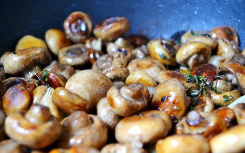 与百里香和大蒜在平底锅里的烤的蘑菇香菇