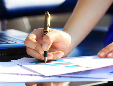 用在办公室里的钢笔写字的女商人照片