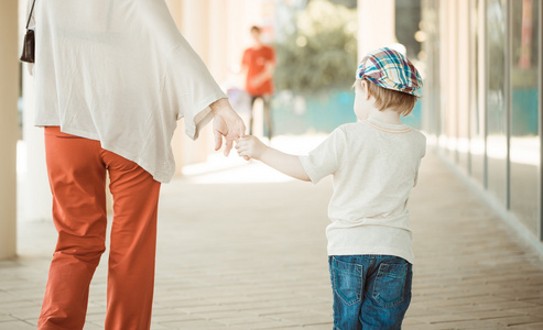 小男孩牵着妈妈的手母亲牵着她的孩子的手年轻的妇女与孩子的扁平风格