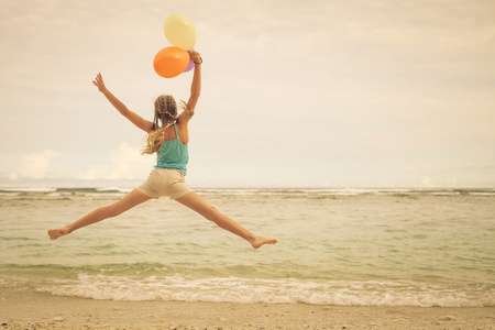 女孩与气球跳上海滩，蓝色的海岸，在苏