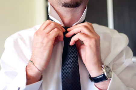 固定黑色领带上白衬衫的商人。新郎在婚礼当天固定领带，老式的影响