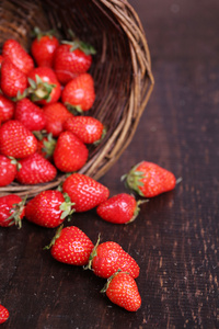在木制的背景上的柳条篮子里的甜草莓成熟