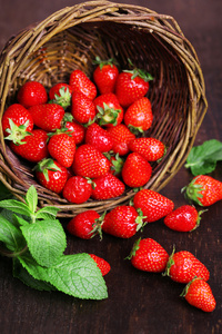 在木制的背景上的柳条篮子里的甜草莓成熟