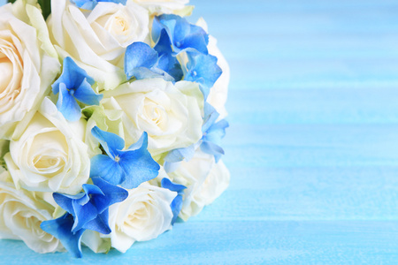 用蓝色木制的桌子上玫瑰的美丽婚礼花束