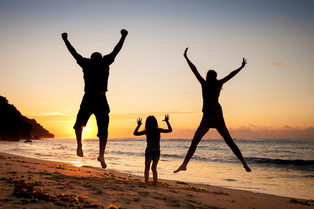 幸福的家庭，在一天的时间在沙滩上跳跃