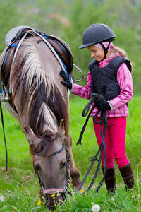 马和骑师的小女孩放牧这匹马在草地上
