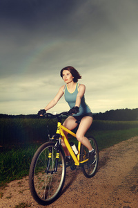 沿着乡间小路骑在自行车上的女孩