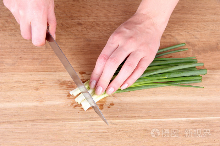 女手割韭菜在砧板上