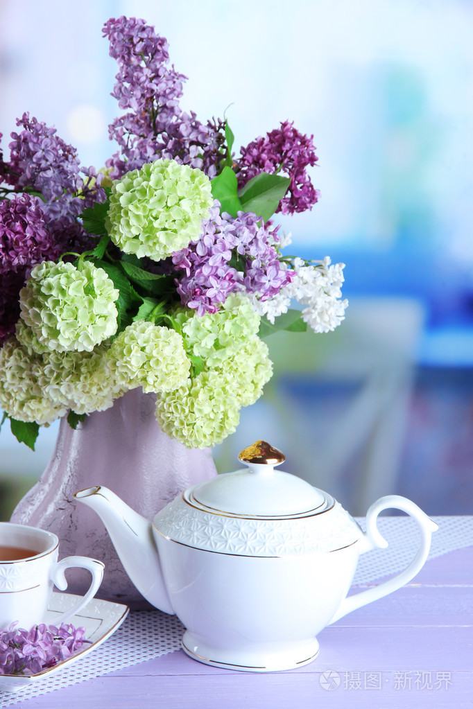 组成与茶壶, 杯子和美丽的春天鲜花插在花瓶里,木制的桌子,在明亮的