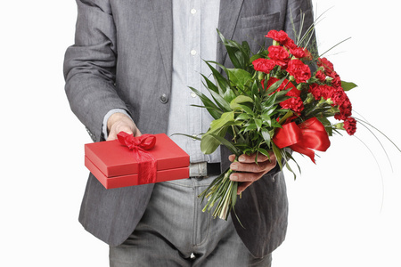 男子手持束红色的康乃馨和大红色的礼品盒