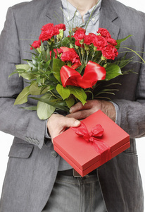 男子手持束红色的康乃馨和大红色的礼品盒