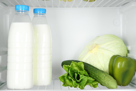 牛奶瓶 蔬菜和水果中打开冰箱。重量损耗的饮食概念