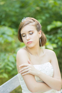 自然美丽的年轻新娘的画像。女孩坐在公园的长椅上
