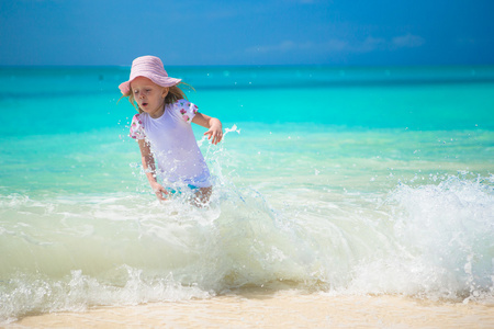快乐的小女孩在异国风情的沙滩在浅水里玩