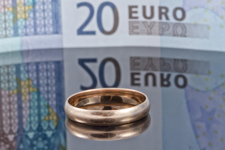 欧元纸币与反射背景上的金戒指
