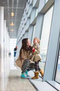 母亲和小女儿在机场航站楼窗外望去