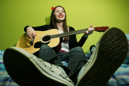 年轻的黑发女人床上弹吉他
