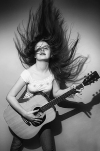 年轻的妇女疯狂地演奏吉他黑和白色