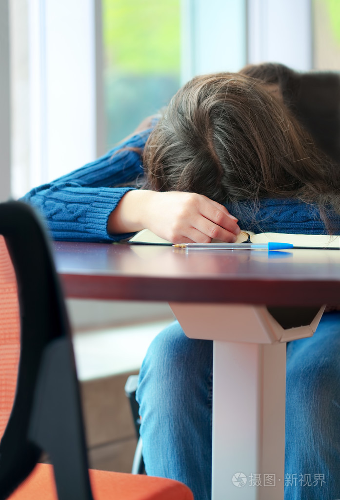 年轻的大学或高中的学生在桌上睡着了