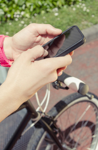 嬉戏女人寻找智能手机的单手自行车
