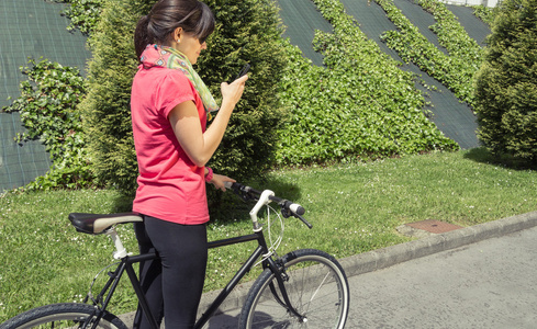 嬉戏女人寻找智能手机的单手自行车