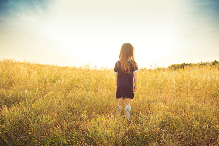 小女孩用长长的头发,穿一件蓝色的衣服费用字段中的背和期待照片