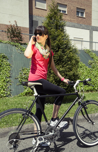 嬉戏女人用单手自行车通过电话呼叫