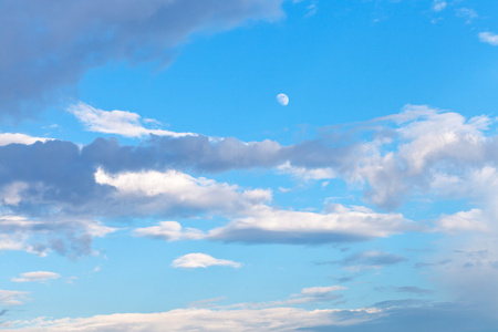 蓝色傍晚天空中的月亮和灰色的云