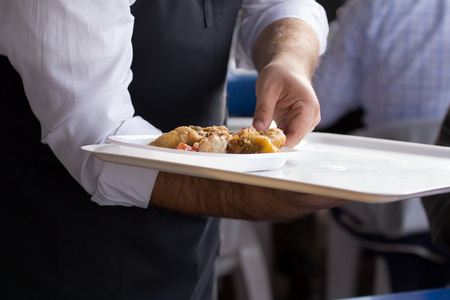 服务员端着托盘的食物照片