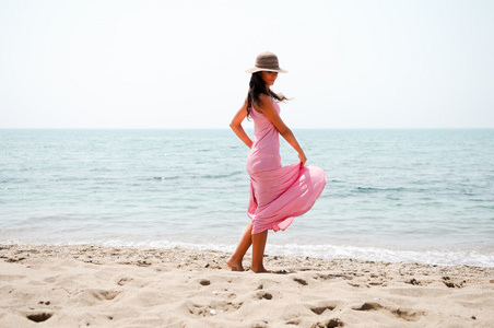 美丽的女人，与热带的 b 上的粉红色的长礼服和太阳帽子