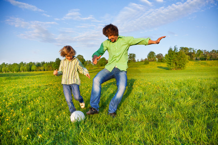 父亲和孩子一起在公园踢足球
