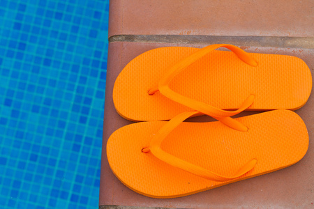 橙色拖鞋在水池边