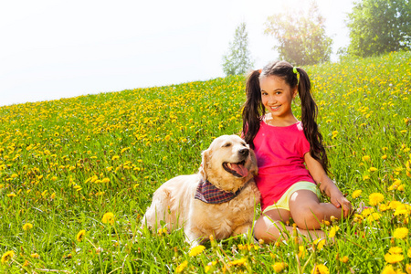 快乐的女孩抱狗坐在草地上