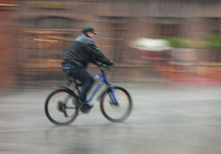 cyklist Rider genom gatorna p en regnig dag